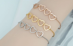 Detailed view of interconnected heart charms on rose gold, gold, and silver chain bracelets