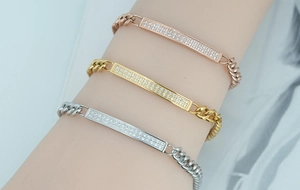 Close-up of minimalist curb chain bracelets with crystal bars in gold, rose gold and silver