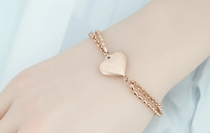 Dettaglio del bracciale a doppio strato in oro rosa con ciondolo a cuore spazzolato