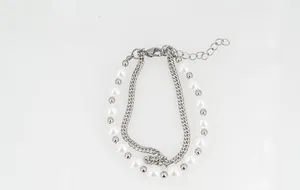 Vue détaillée du bracelet double couche en acier titane avec perles blanches et gourmette
