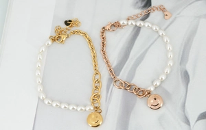 Détail de bracelets en perles or et or rose avec breloque smiley et chaîne métallique