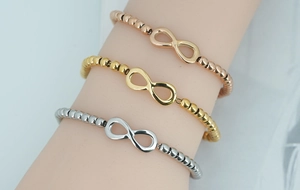 Detailed close-up of infinity symbol bracelets in gold, rose gold and silver finishes