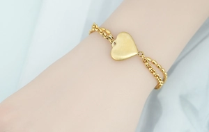 Primo piano di un bracciale a doppio strato in titanio dorato con cuore al polso
