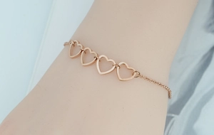 Detailed view of rose gold hollow heart links on a stainless steel chain on wrist