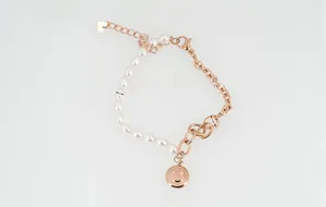 Détail du bracelet chaîne en perles or rose avec pendentif smiley et extension de coeur