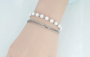 Détail d'un bracelet double couche avec perles blanches et chaîne à maillons argent