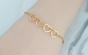 Close-up of golden hollow heart chain bracelet with adjustable link on female wrist