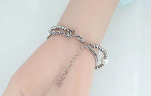 Détail d'un bracelet multicouche en acier titane avec perle blanche et fermoir réglable