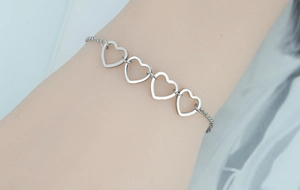 Polished stainless steel bracelet featuring four hollow heart links on a delicate chain