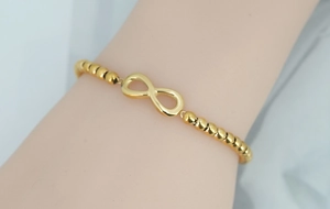 Detailed view of infinity symbol gold beaded bracelet with shiny stainless steel finish