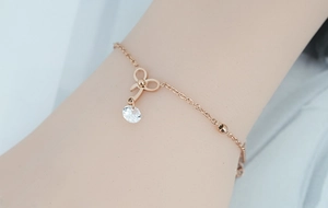 Gros plan d'un bracelet nœud en or rose avec pendentif en zircon sur chaîne perlée
