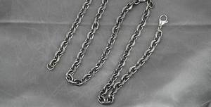 Detail view of a vintage dark grey stainless steel Cuban link chain with lobster clasp