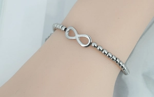 Macro shot of silver infinity symbol bracelet with cylindrical beads on a wrist
