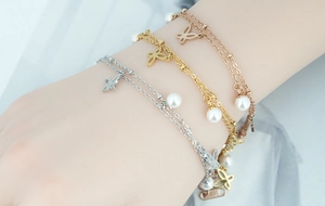 Détail du bracelet double couche en acier inoxydable avec papillon et perle blanche