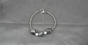 Detail of dice charms and white pearls on a silver stainless steel beaded necklace