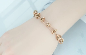 Close-up of a double-layered rose gold knot chain bracelet worn on a woman's wrist