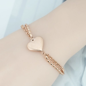 Elegante bracciale a doppio strato con cuore in acciaio al titanio oro rosa indossato al polso