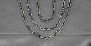 Detailed view of heavy vintage oxidised titanium steel Cuban chains on silk
