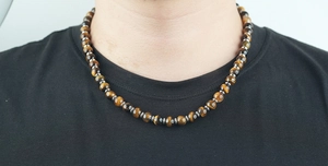 Détail d'un collier en perles d'oeil de tigre de 8mm avec entretoises métalliques sur un homme