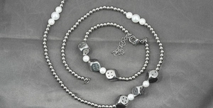 Detail of silver bead and pearl necklace featuring unique metallic dice pendants and lobster clasp