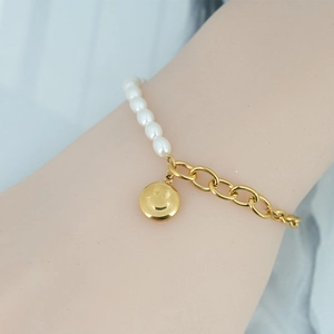 Bracelet en perles et chaîne dorée avec pendentif smiley porté au poignet d'une femme