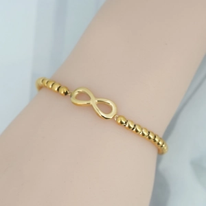 Elegant gold infinity charm bracelet with polished round beads for women on wrist