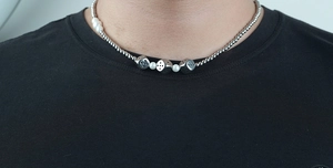 Detail of dice charms and pearls on a stainless steel Cuban chain necklace for men and women