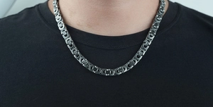 Macro shot of a thick silver Byzantine titanium steel chain necklace on a black shirt
