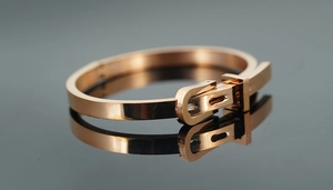 Vue macro d'un bracelet en acier poli doré rose avec un fermoir style boucle de ceinture