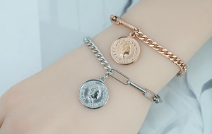 Close-up of gold and silver Elizabeth II coin pendants on curb and paperclip link chains