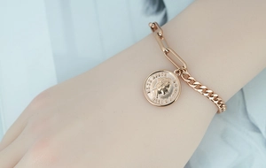 Close-up of rose gold coin bracelet with Elizabeth II pendant and mixed link chain