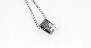 Detail of stainless steel ring pendant with engraved prayer and silver cross charm