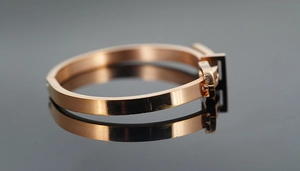 Détail d'un bracelet poli en or rose avec design de boucle de ceinture et reflets chic