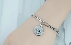Detail of a retro Elizabeth II coin pendant on a mixed link steel chain bracelet