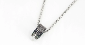 Macro detail of stainless steel box chain and black cylindrical cross pendant with prayer