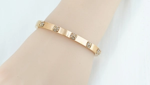 Close-up of rose gold stainless steel cuff bracelet with cross diamond square patterns