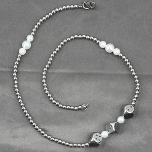 Cuban link necklace with white pearls and three metal dice pendants on gray background