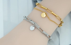 Gros plan de bracelets en couches or et argent avec pendentifs ronds sur un poignet