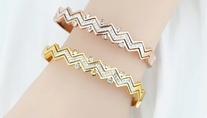 Dettaglio di bracciali impilati a onde in oro e oro rosa in acciaio inossidabile con zirconi