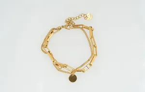 Vue détaillée du bracelet à double chaîne dorée avec pendentifs disque et cœur