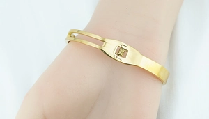 Detail of gold butterfly bracelet with secure snap closure and hollow dual-line design