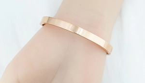 Bracciale rigido aperto in acciaio inossidabile oro rosa lucido indossato da donna