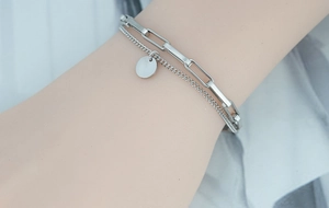 Détail d'un bracelet multicouche en argent avec chaîne trombone et pendentif cercle épuré