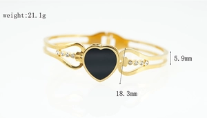 Detail view of heart-shaped gold bracelet with black inlay and crystal rhinestones