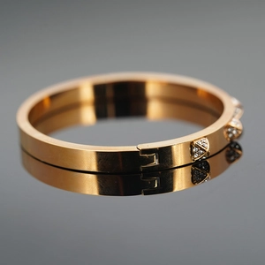 Polished gold stainless steel cross bracelet with embedded crystals and hinge closure