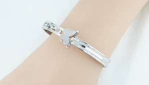 Detail of silver stainless steel butterfly cuff bracelet with white zircon pavé on model wrist