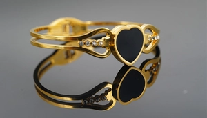Detailed close-up of golden heart bangle with black inlay and sparkling zircon accents
