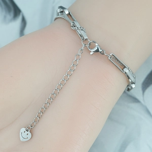 Bracelet double chaîne argentée avec pendentif cœur souriant sur poignet féminin