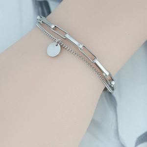 Bracelet double couche argenté avec chaîne trombone et pendentif rond porté au poignet