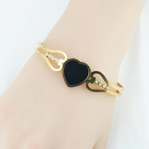 Gold open bangle for women featuring a black heart charm and white crystal accents